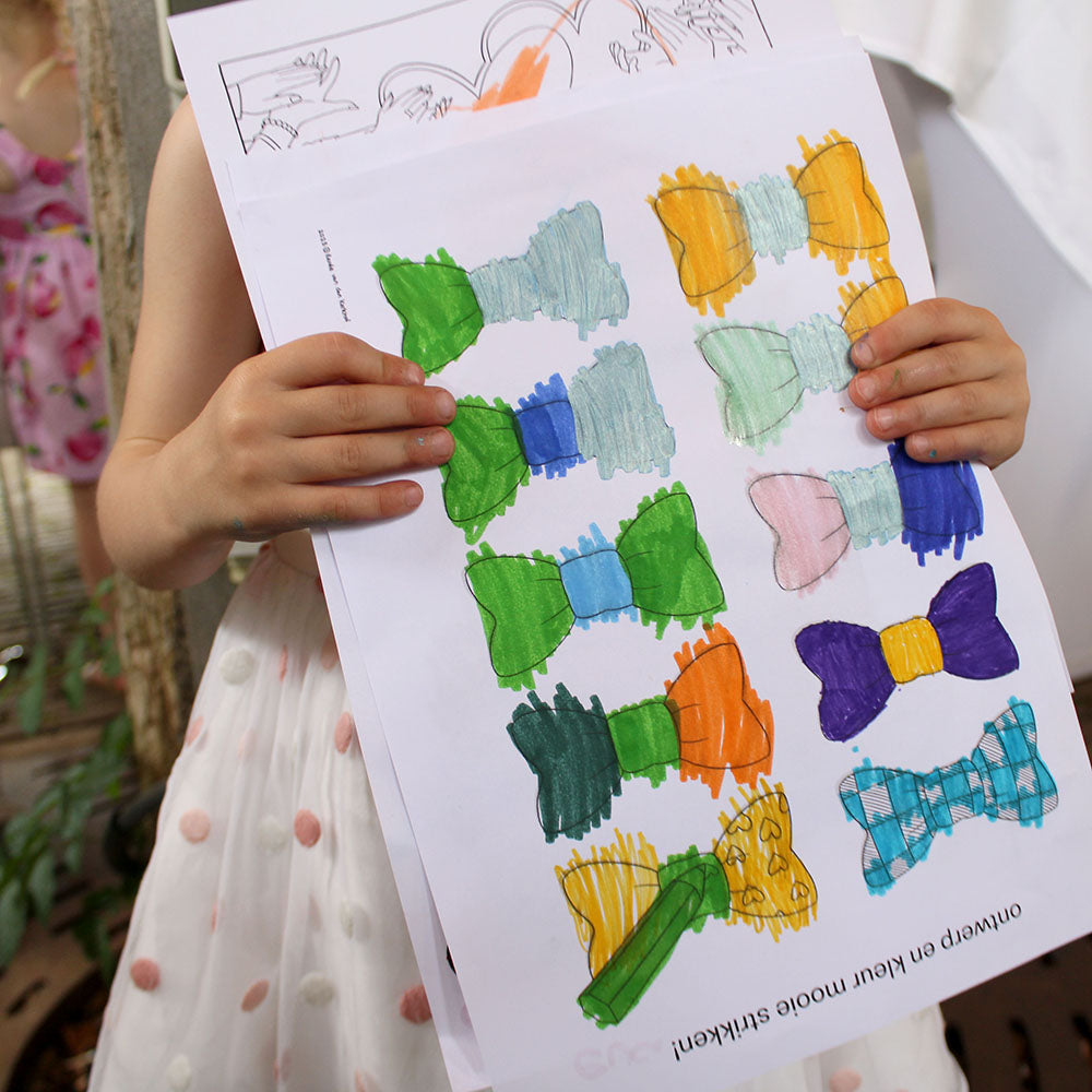 Child holding colouring pages in wedding theme.
